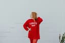 Model wearing a red pima-cotton sweater dress with big block white 'Tomato Soup' text during the summer months.